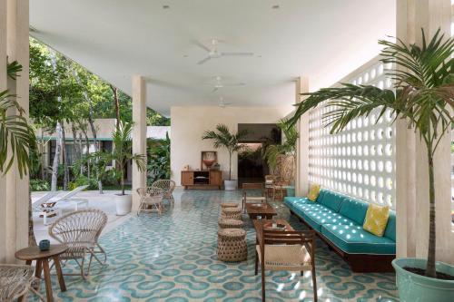 un patio con sofá, mesas y sillas en Hotel Tiki Tiki Tulum, en Tulum
