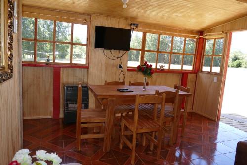 a dining room with a table and chairs and a television at Parques de Afunalhue in Licán Ray