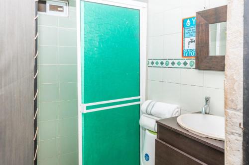 a bathroom with a green shower door next to a sink at Casita mi nuevo amanecer in Santa Marta