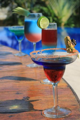 four cocktails on a wooden table with drinks at Hotel Villa Mercedes Palenque in Palenque