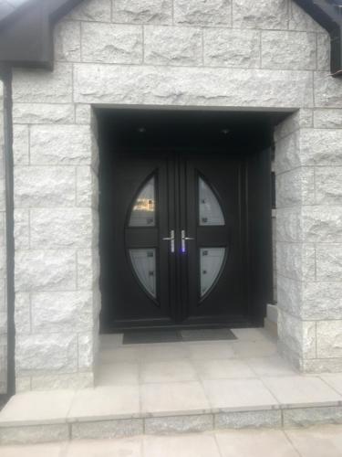 a black door with a window in a stone wall at Browns in Peterhead