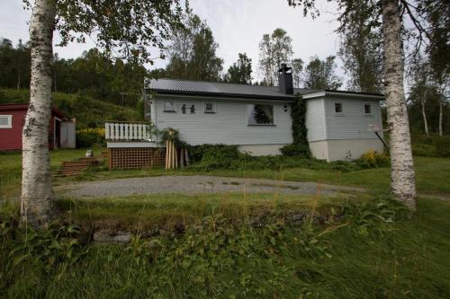 a white house in a yard with trees at Midt Troms Perle in Finnsnes