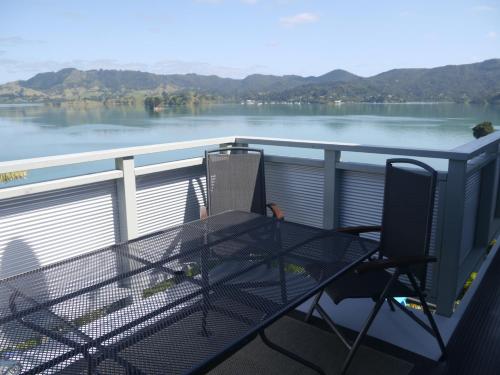a table and chairs on a balcony with a view of a lake at Pacific Harbour Lodge in Whangaroa