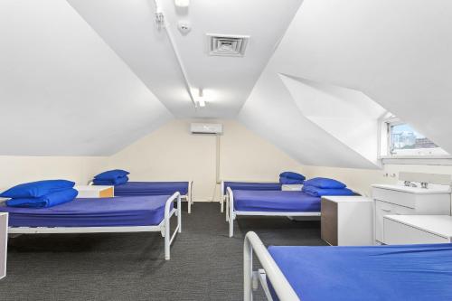 una camera con tre letti con cuscini blu di Summer House Kings Cross, Sydney a Sydney