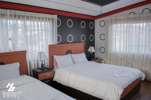 a bedroom with two beds and two windows at Belmont B&B in La Paz