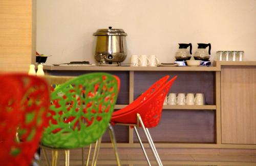 two red and green chairs in front of a counter at Zodiak Paskal by KAGUM Hotels in Bandung