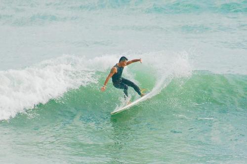 a man riding a wave on a surfboard in the ocean at On Board Hostel in Manzhou