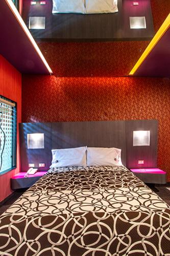 a bedroom with a bed with a red wall at HOTEL ZARAGOZA INN BOUTIQUE in Mexico City