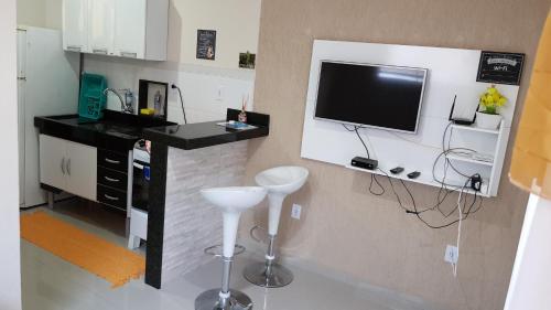 a kitchen with a tv and a counter with a stool at Casa em Arraial do Cabo in Arraial do Cabo