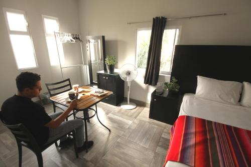 a man sitting at a table in a bedroom at Hotel del Refugio in Guadalajara