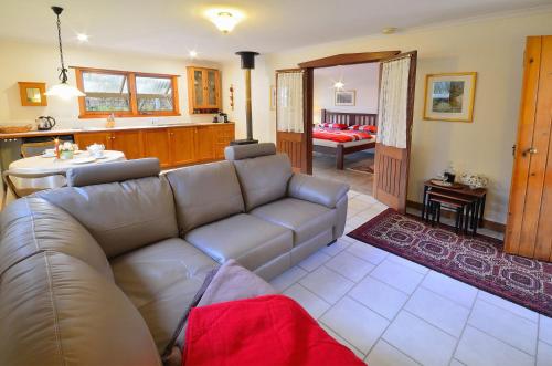 Stephanette's Cottage في Lights Pass: غرفة معيشة مع أريكة ومطبخ