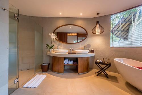 a bathroom with two sinks and a tub and a mirror at tanadewa Resort Ubud Bali by Cross Collection in Ubud