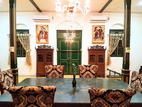 a dining room with a table and chairs and a green door at nDalem Gamelan in Yogyakarta