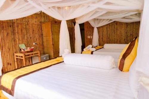 two beds in a room with white curtains at Tam Coc Wonderland Bungalow in Ninh Binh