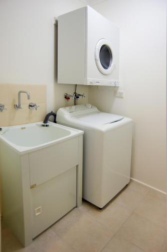a bathroom with a sink and a washing machine at Quest St Kilda Bayside in Melbourne