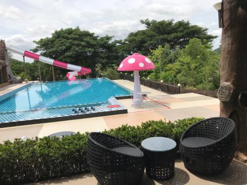 a pool with a pink umbrella and some tables and chairs at Sangchan Garden at Kaeng Krachan in Kaeng Krachan