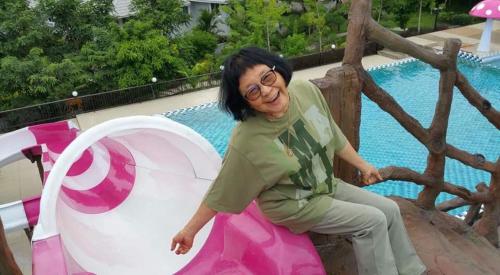 a woman sitting on a pink and white object next to a pool at Sangchan Garden at Kaeng Krachan in Kaeng Krachan