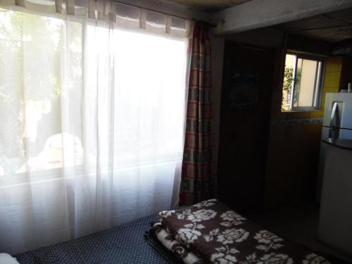 a bedroom with a window with curtains and a bed at Cabañas Mirador de Soledad in El Quisco
