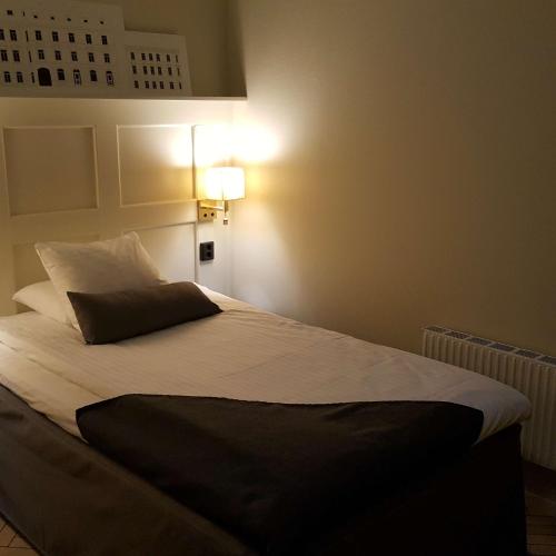 a bed in a bedroom with a light on the wall at Best Western Hotel Baltic in Sundsvall
