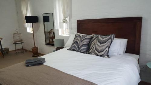 Schlafzimmer mit einem weißen Bett mit einem Kopfteil aus Holz in der Unterkunft loft 33 in Pietermaritzburg