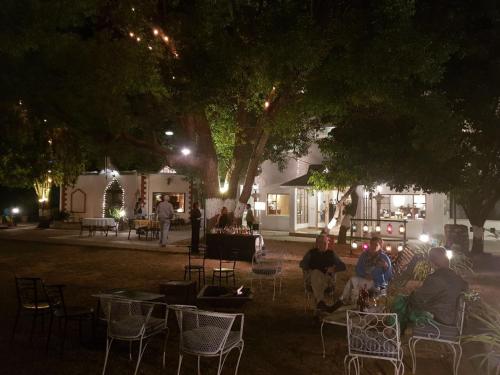 a group of people sitting in chairs under trees at night at WelcomHeritage Judges Court in Kangra
