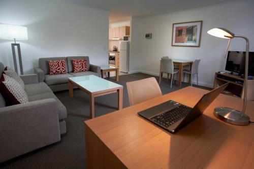 a living room with a couch and a laptop on a table at Quest St Kilda Bayside in Melbourne
