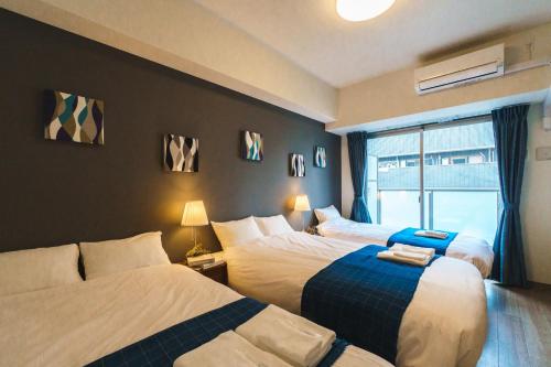Habitación de hotel con 2 camas y ventana en IKIDANE Residential Hotel SHIMANOUCHI en Osaka