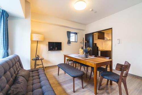 a living room with a couch and a table and chairs at IKIDANE Residential Hotel SHIMANOUCHI in Osaka