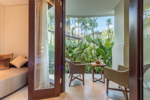 a room with a balcony with a bed and a table at tanadewa Resort Ubud Bali by Cross Collection in Ubud