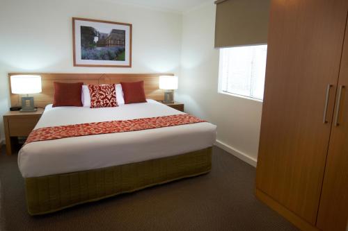 a bedroom with a large bed with red pillows at Quest St Kilda Bayside in Melbourne