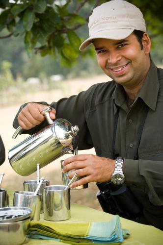 a man in a hat is pouring liquid into a cup at Baghvan Pench National Park - A Taj Safari Lodge in Behrai