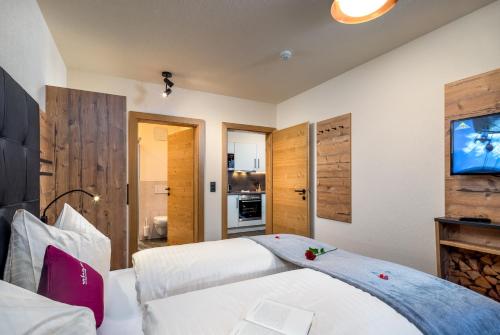 a bedroom with two beds and a flat screen tv at Alpin Chalet am Burgsee in Ladis