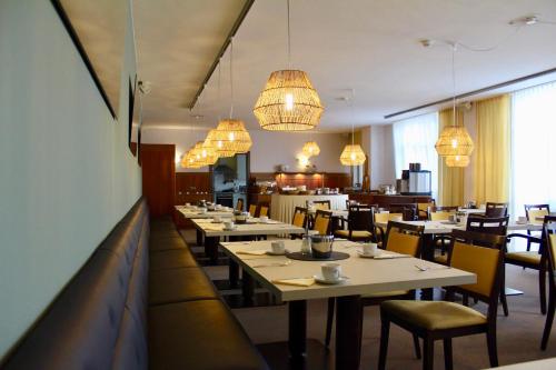 un comedor con mesas, sillas y lámparas de araña en Hotel Garni Max Zwo en Dingolfing