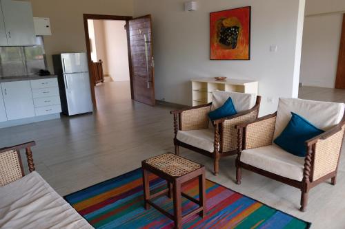 a living room with chairs and a table and a kitchen at Twenty-Two Weligambay in Weligama