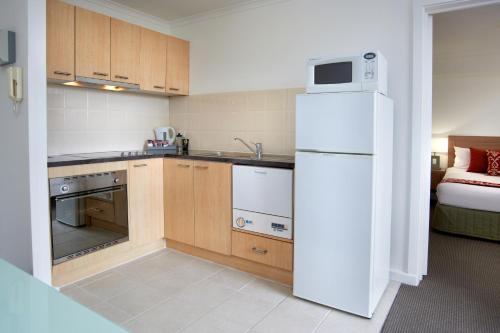 a kitchen with a white refrigerator and a bed at Quest St Kilda Bayside in Melbourne