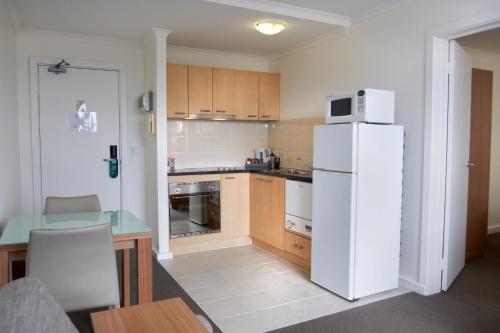 a kitchen with a white refrigerator and a table at Quest St Kilda Bayside in Melbourne