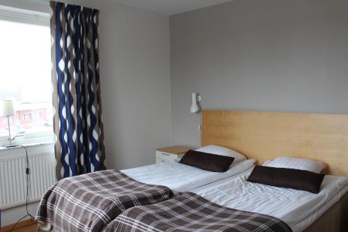 two twin beds in a room with a window at Hotell Åsen in Anderstorp