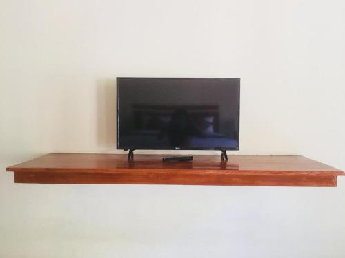telewizor z płaskim ekranem na drewnianej półce w obiekcie The Tinsi w mieście Nusa Penida