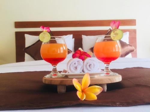 two glasses of juice and towels on a tray on a bed at The Tinsi in Nusa Penida