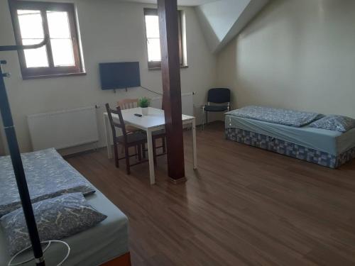 a room with two beds and a table and a desk at Penzion V Zatáčce in Plzeň