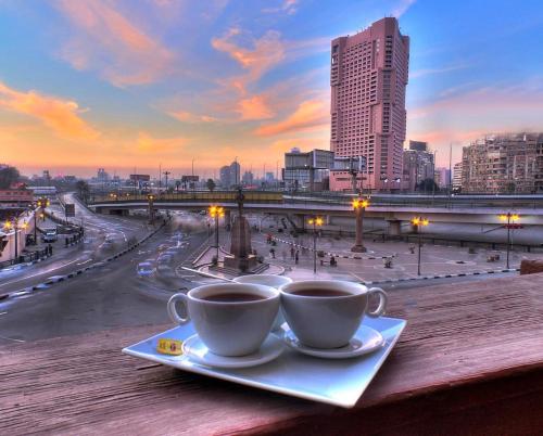 two cups of coffee on a table with a view of a city at Tahrir Plaza Suites - Museum View in Cairo