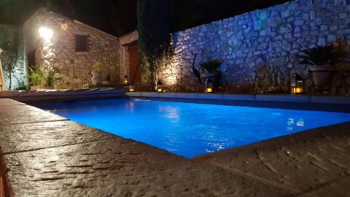 - une piscine avec un mur en pierre la nuit dans l'établissement La bastide Maë, à Saint-Remèze
