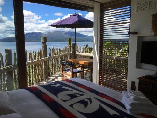 a bedroom with a balcony with a table and an umbrella at te Whare -Lake Tarawera tree-top nest in Lake Tarawera
