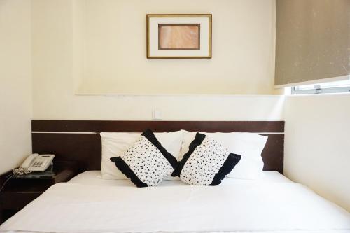 a bed with black and white pillows and a phone at Metacity MK 名廸旺角 in Hong Kong