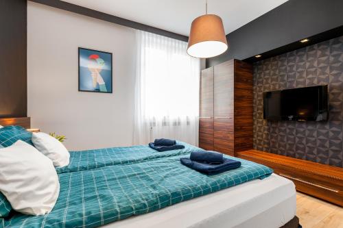 a bedroom with a bed with blue sheets and a flat screen tv at Apartamenty Black&White in Gdynia