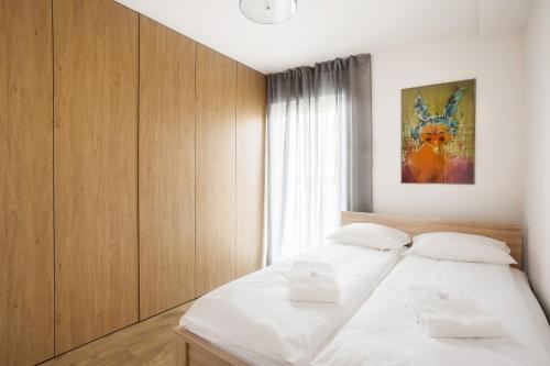 ポズナンにあるApartment Poznań Garbaryの白いベッド1台、木製キャビネットが備わるベッドルーム1室が備わります。