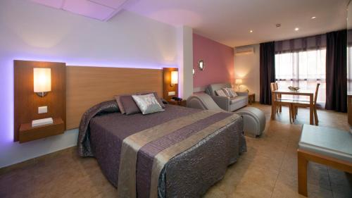 a hotel room with a large bed and a chair at Leo Punta Umbría - Adults Only in Punta Umbría