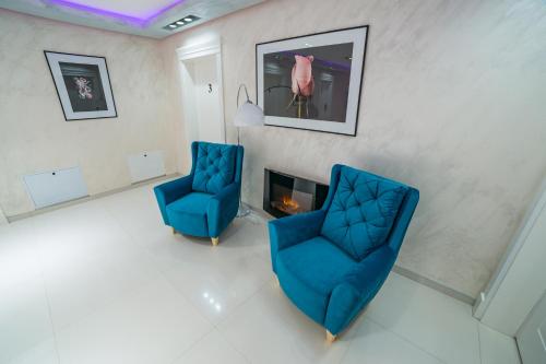 two blue chairs in a living room with a fireplace at Motel Felikitas in Laktaši