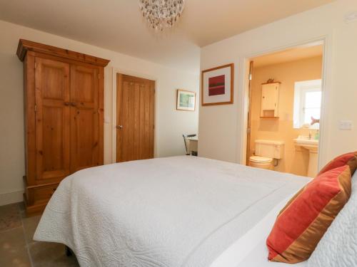 a bedroom with a white bed and a bathroom at Wallerthwaite Barn Cottage in Harrogate