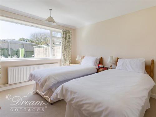 two beds in a bedroom with a window at Hillview Bungalow in Burton Bradstock